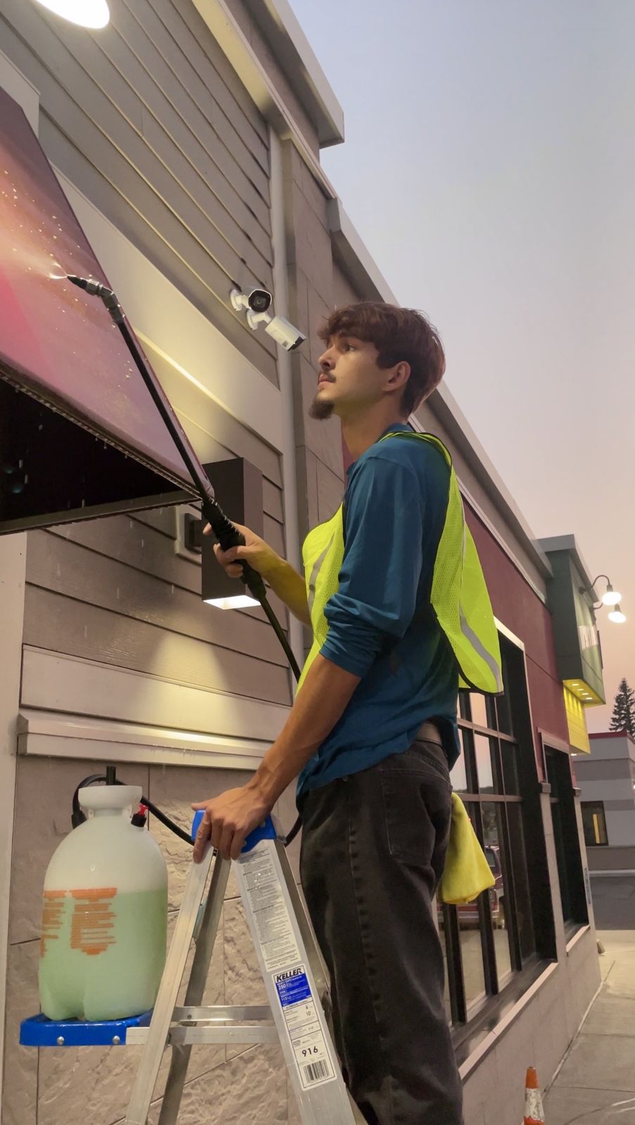 Devan Towslee, owner of Towslee's Got Pressure, soft washing a storefront awning