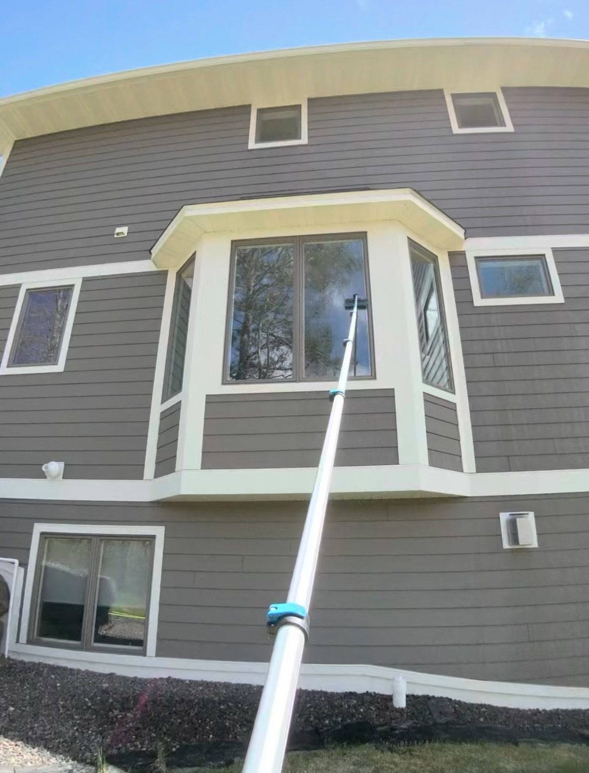 Pure-water pole cleaning upper-story windows on a two-story home in the Duluth area